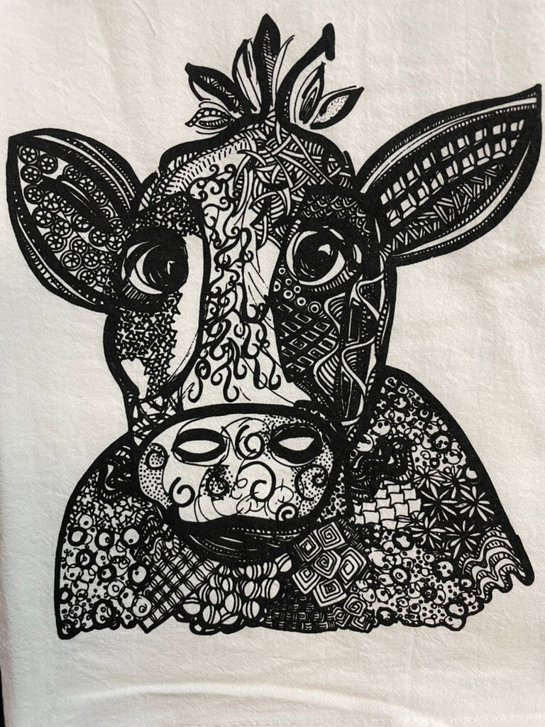 A black and white tea towel featuring a detailed cow design with intricate patterns.