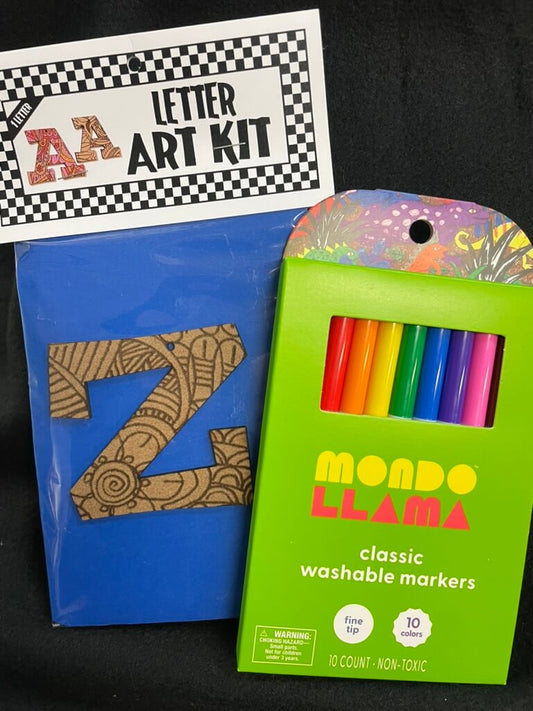 The image shows a part of an art kit with a letter 'Z' shaped template and a set of colorful washable markers. The packaging is predominantly green with a colorful design and text that reads 'A to Z Art Kit by Mando Lama'.