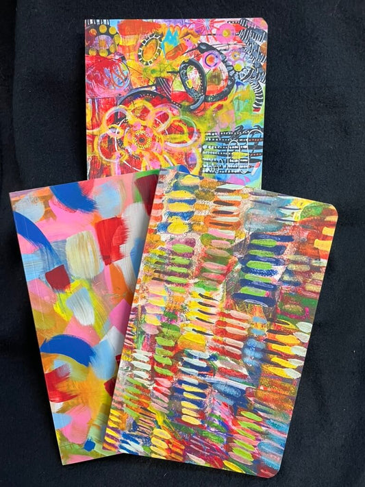 Three colorful abstract art notebooks on a black background